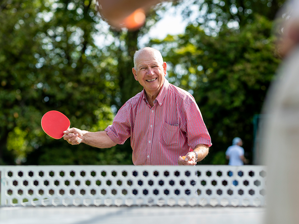 Senior man playing table tennis outside