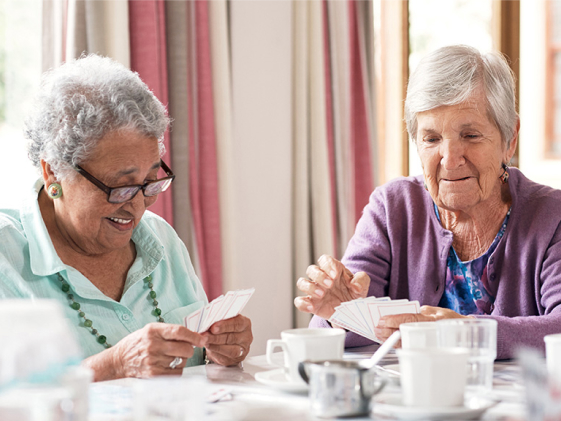 Two senior women playing cards at the dinning table