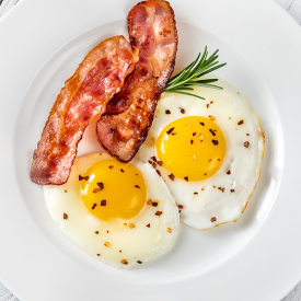 Two eggs sunny side up with two pieces of bacon