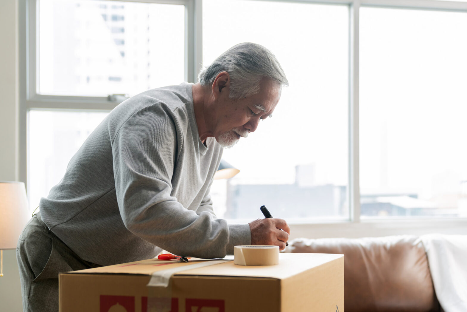 Senior man packing and labeling a moving box