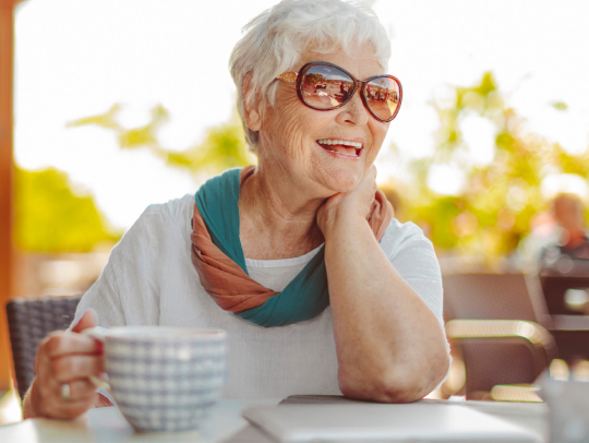 Senior woman wearing shades while having her morning coffee spilling some tea