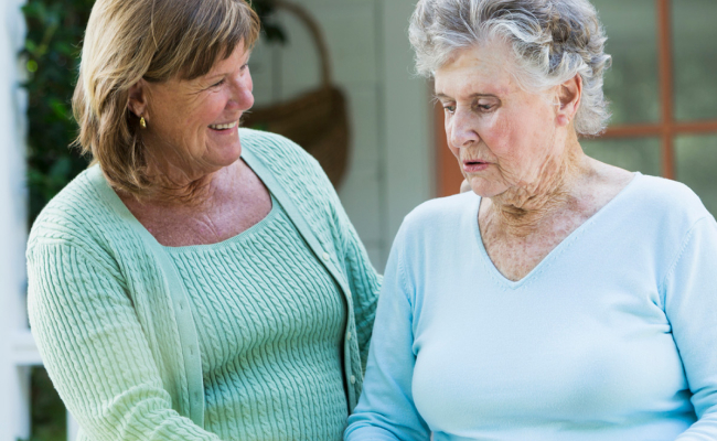 Woman helping senior woman walking with a smile