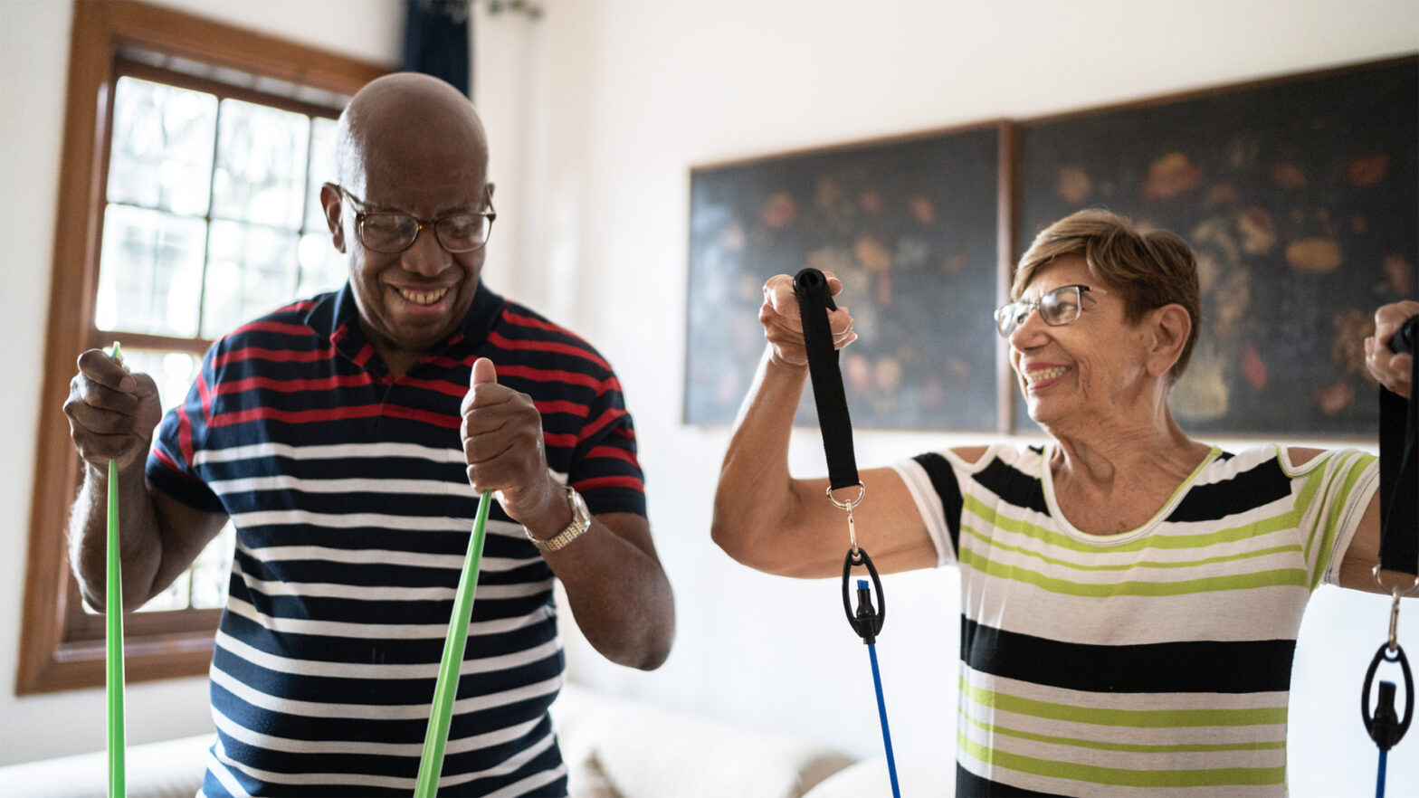 An senior black man and senior white women exercising with bungie cords