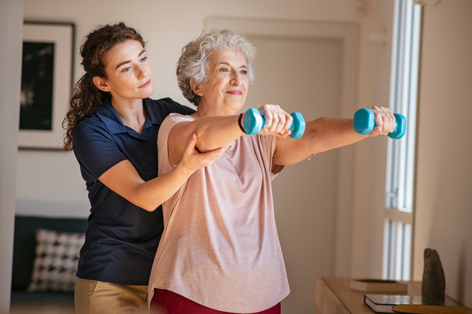 Senior woman being assisted with a community employee doing exercise