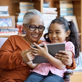 Senior grandmother reading to her granddaughter in the library