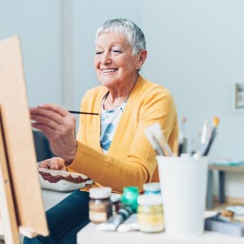 senior white woman painting on canvas
