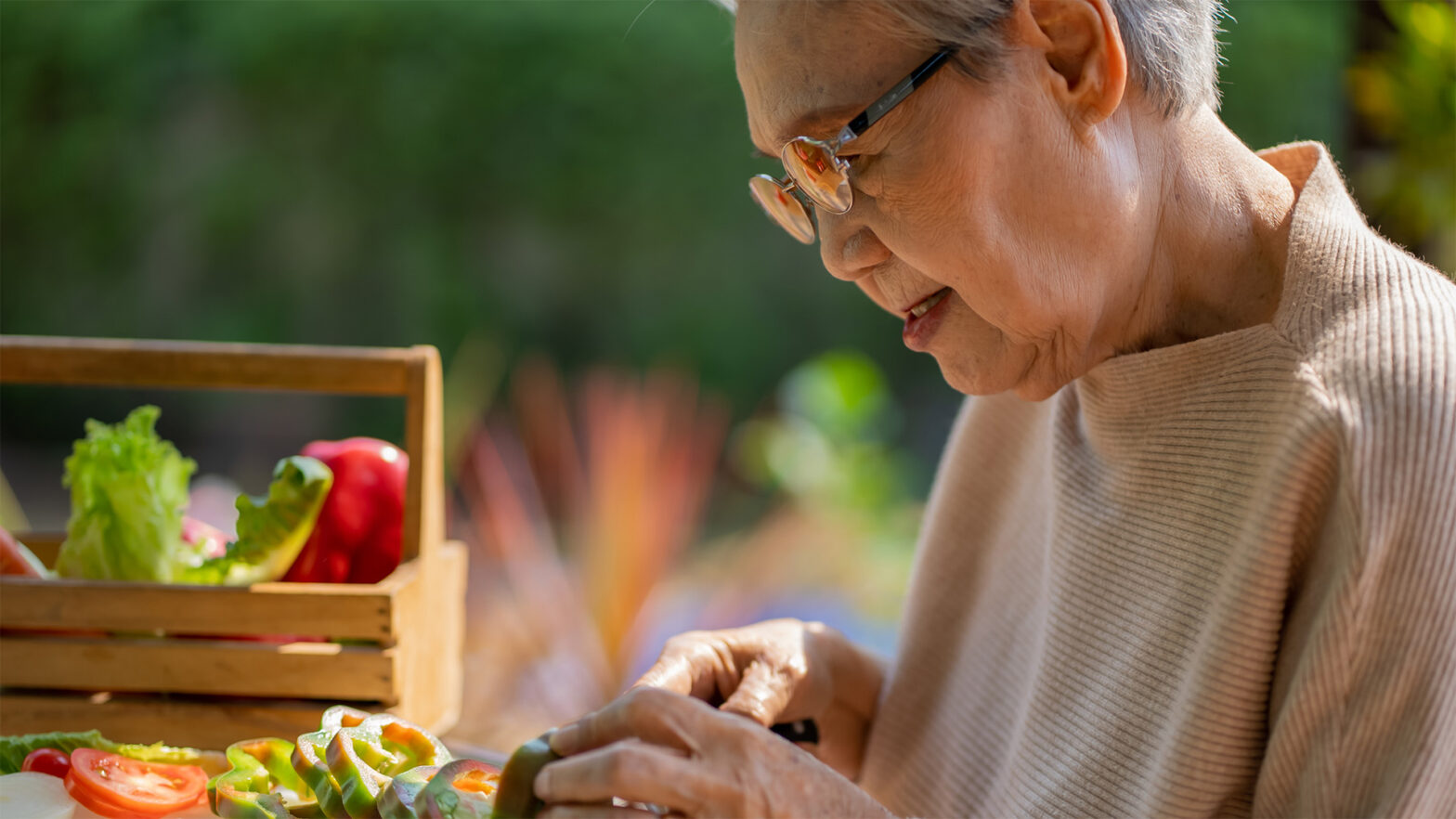 Older woman cutting up fresh vegetables outside