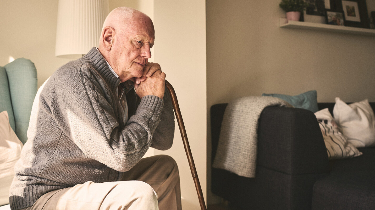 Senior man with cane sitting in his room thinking