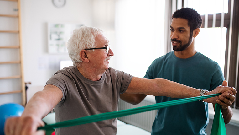 A young physiotherapist exercising with senior patient in a physical room