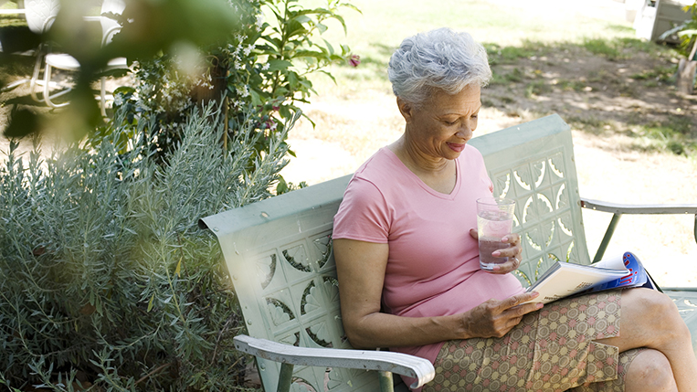 Woman on patio with magazine and glass of water