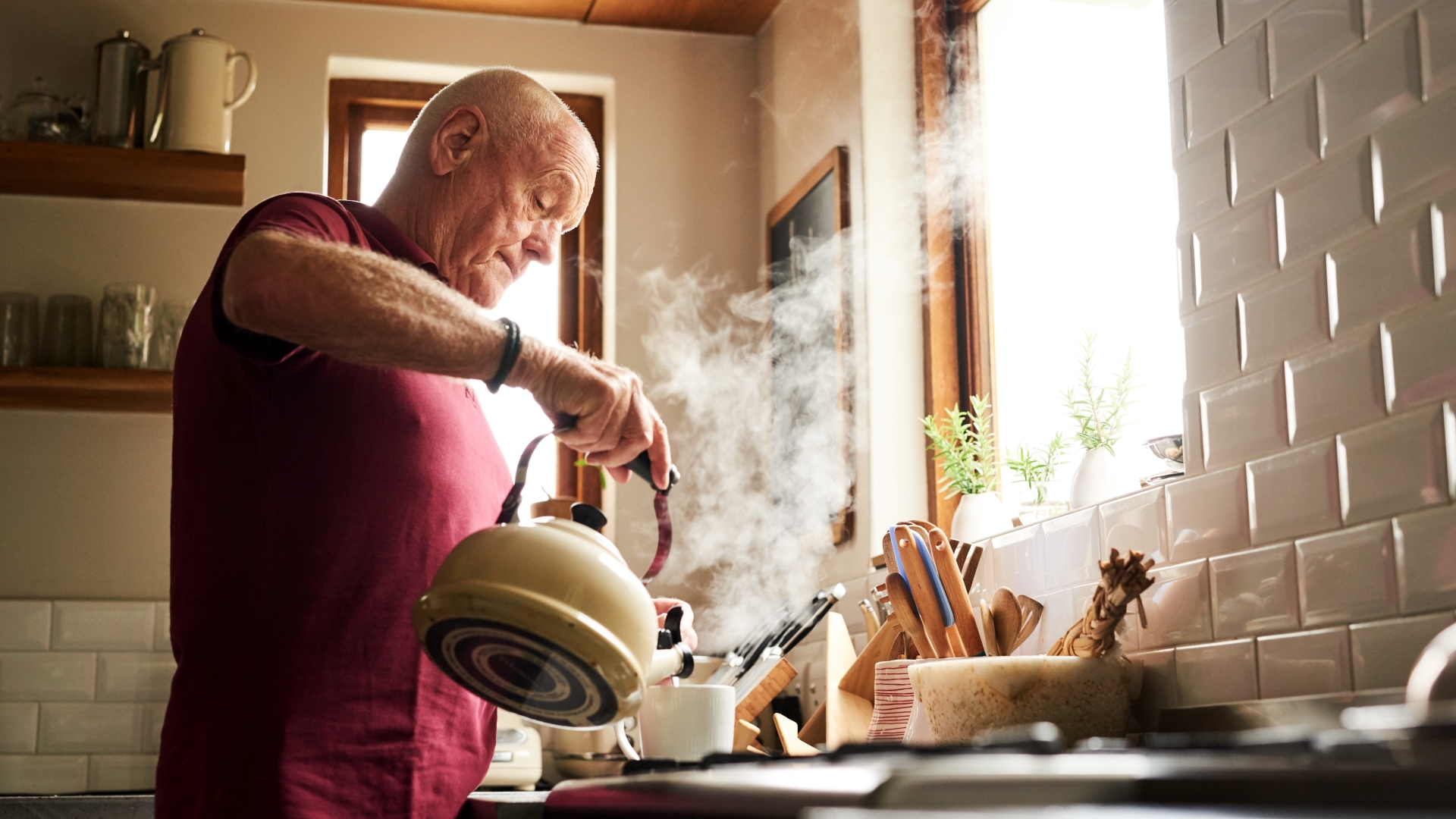 Senior man pouring hot water into a mug for tea