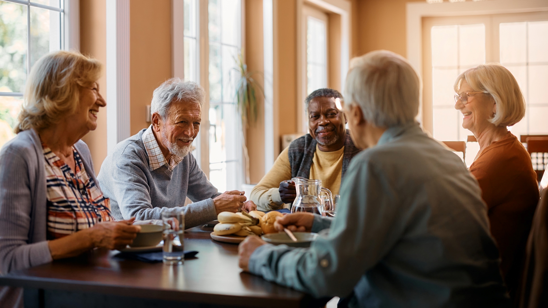 Group of older adults eating soup and socializing at the dinner table