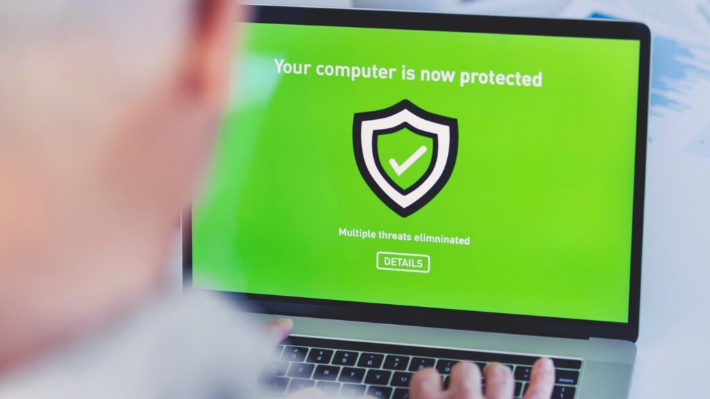 Mature businessman looking at an antivirus security login screen on a computer. There is a shield and protection message on the screen.