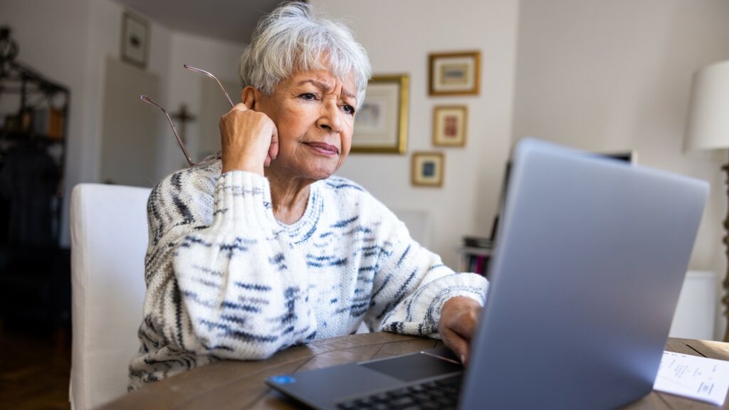 A senior woman with a concerned emotion at her laptop computer