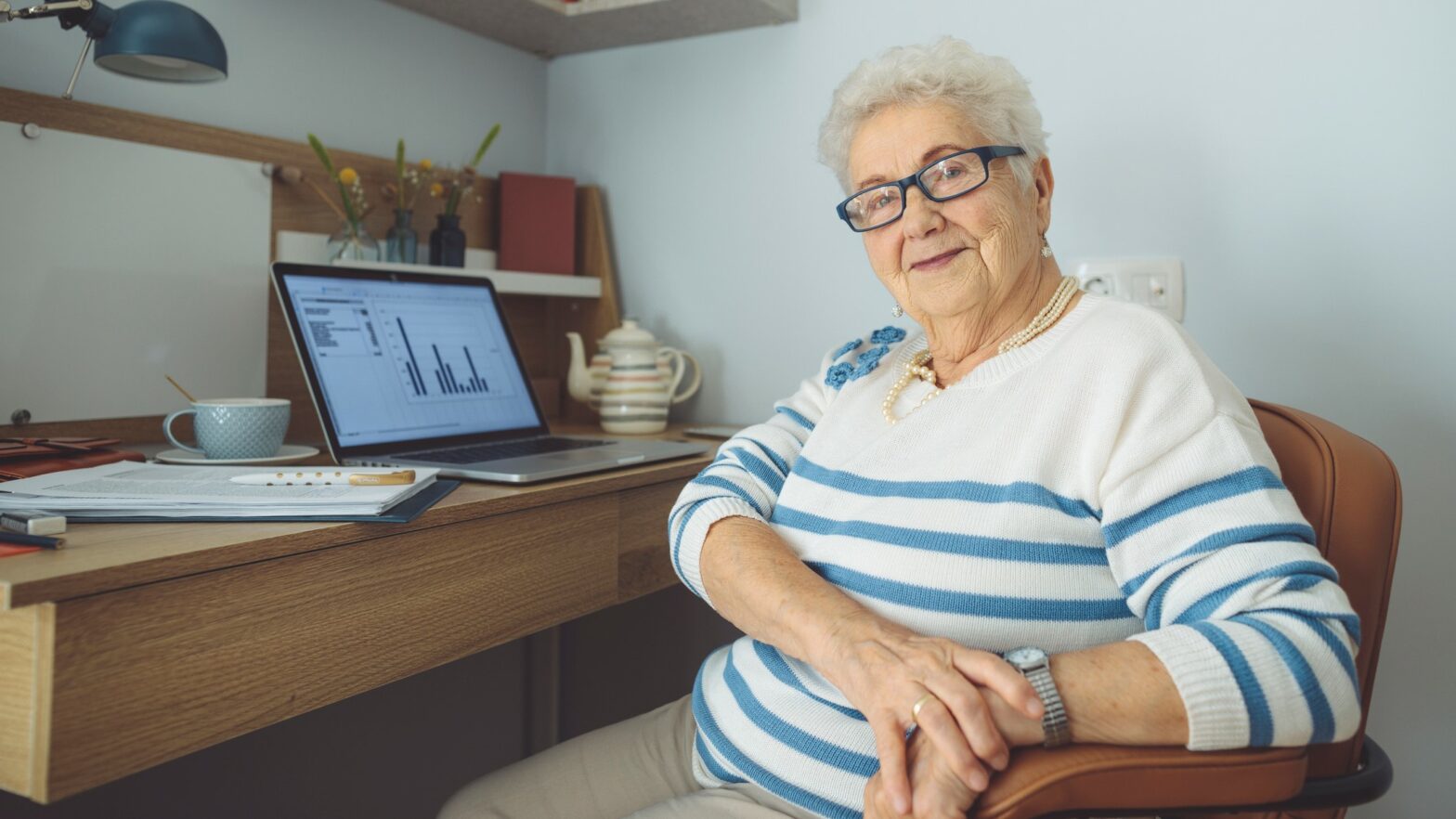 Senior woman sitting at her desk in front of her computer at home