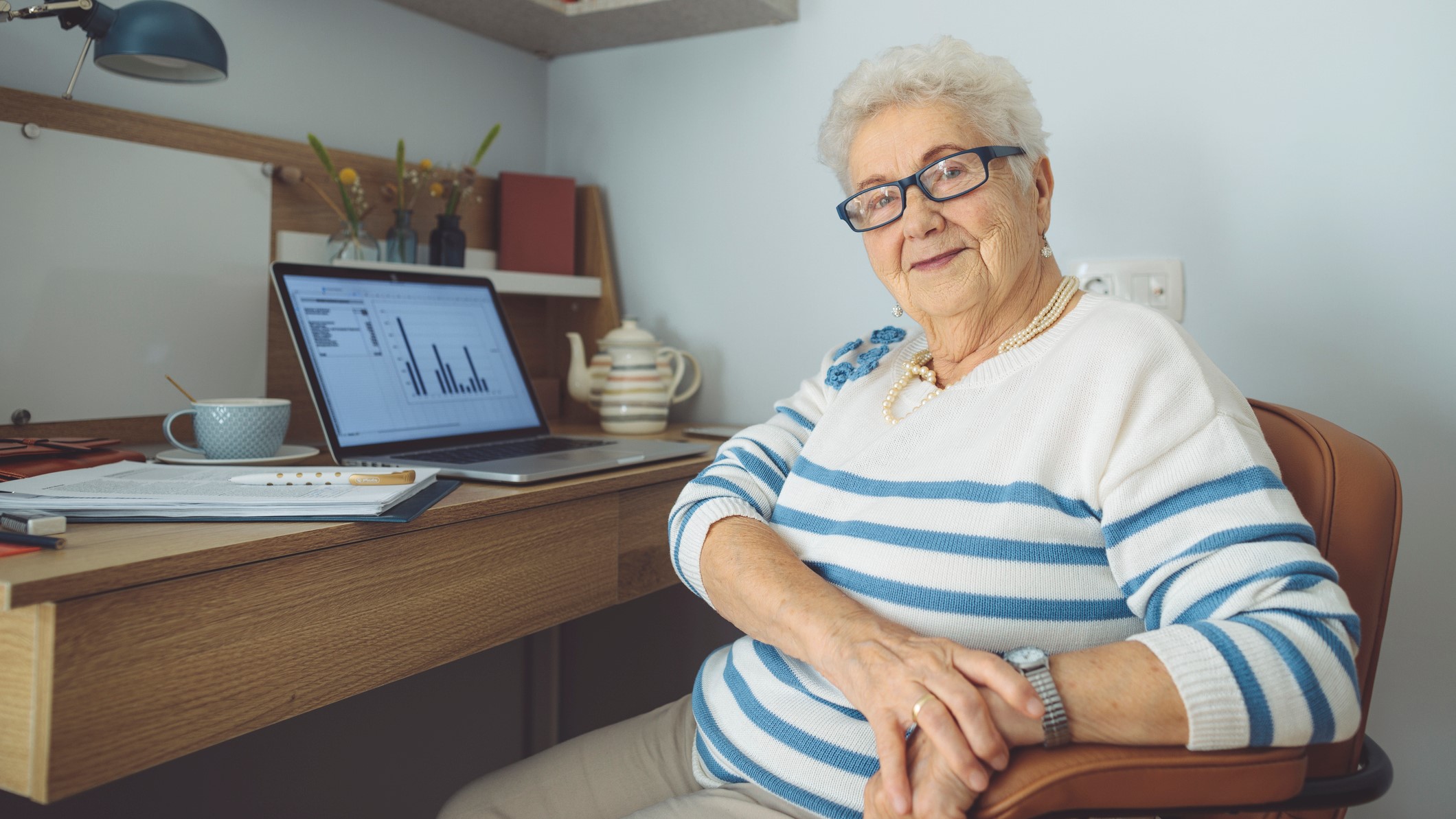 Senior woman sitting at her desk in front of her computer at home