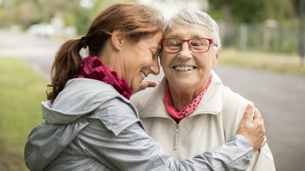 Happy senior woman and caregiver walking outdoors