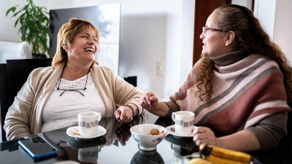 Mature friends talking in the dining room at home