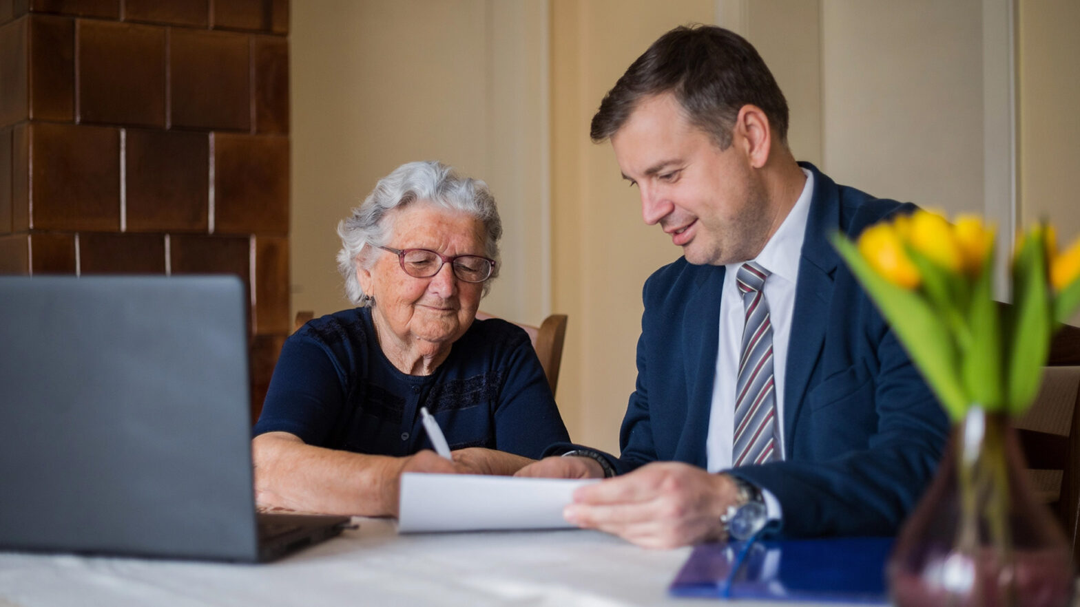 Financial advisor helps and older female client with paperwork