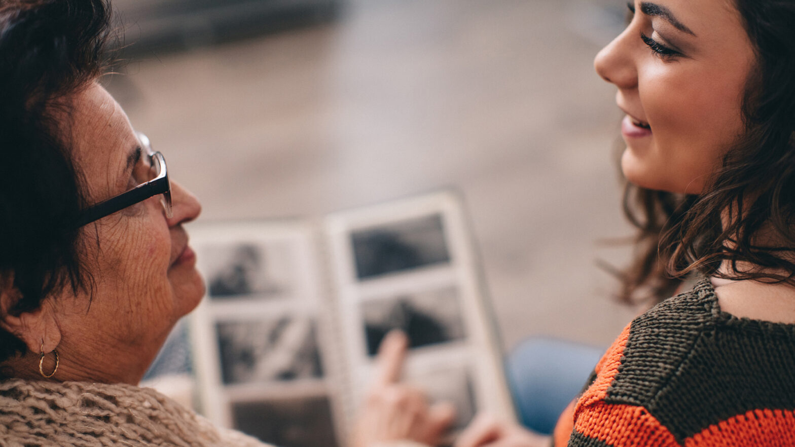 Older woman and younger woman looking over a photobook and discussing its contents