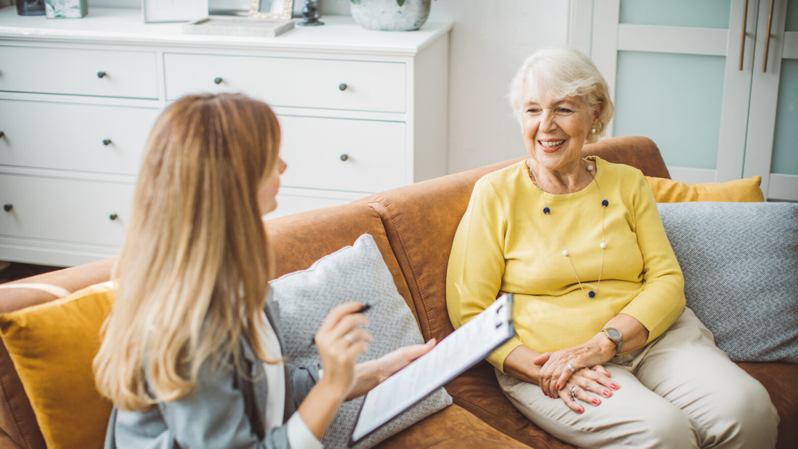 Senior woman talking with female financial or real estate advisor at home.