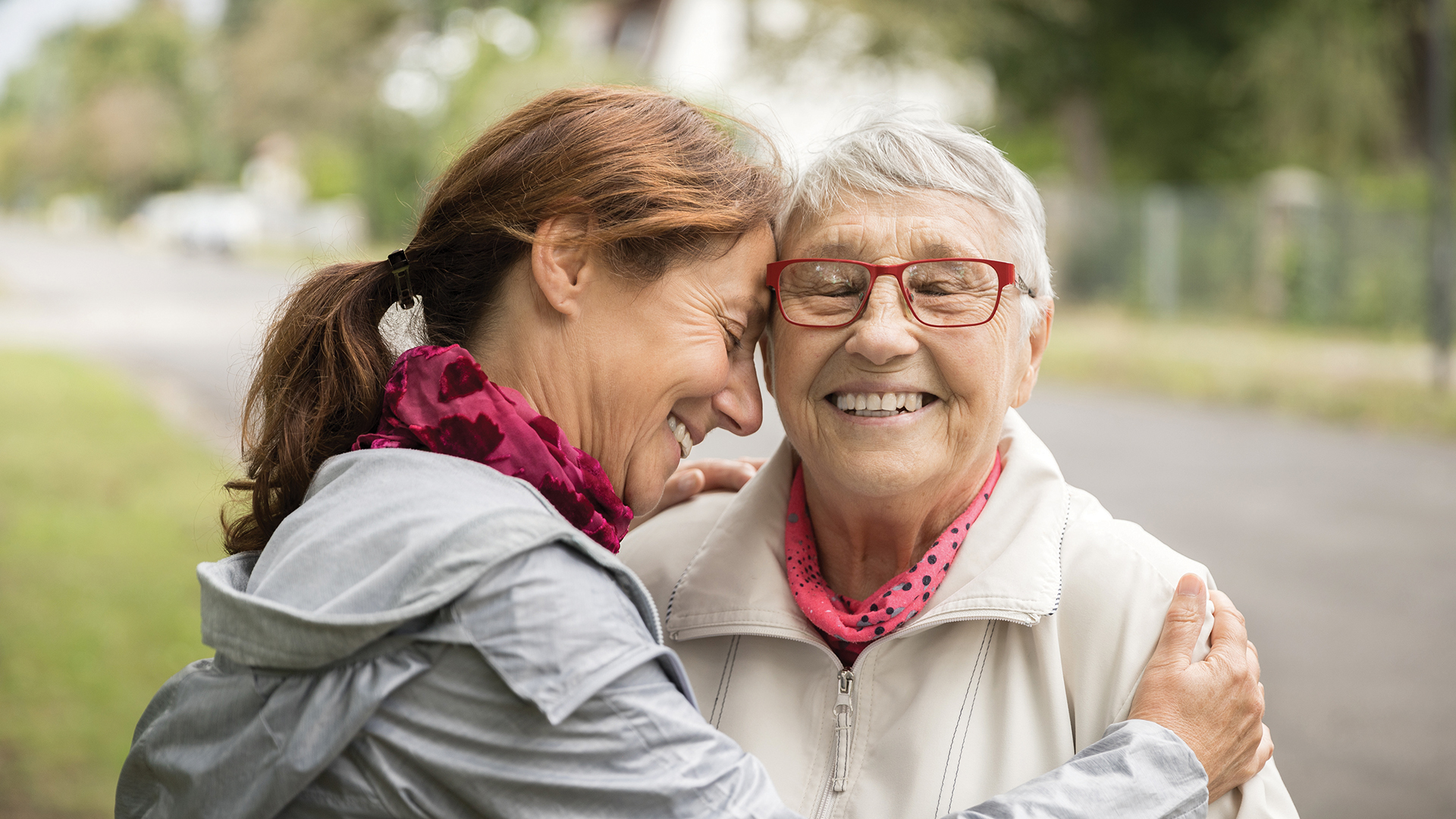 Happy senior woman and caregiver walking outdoors