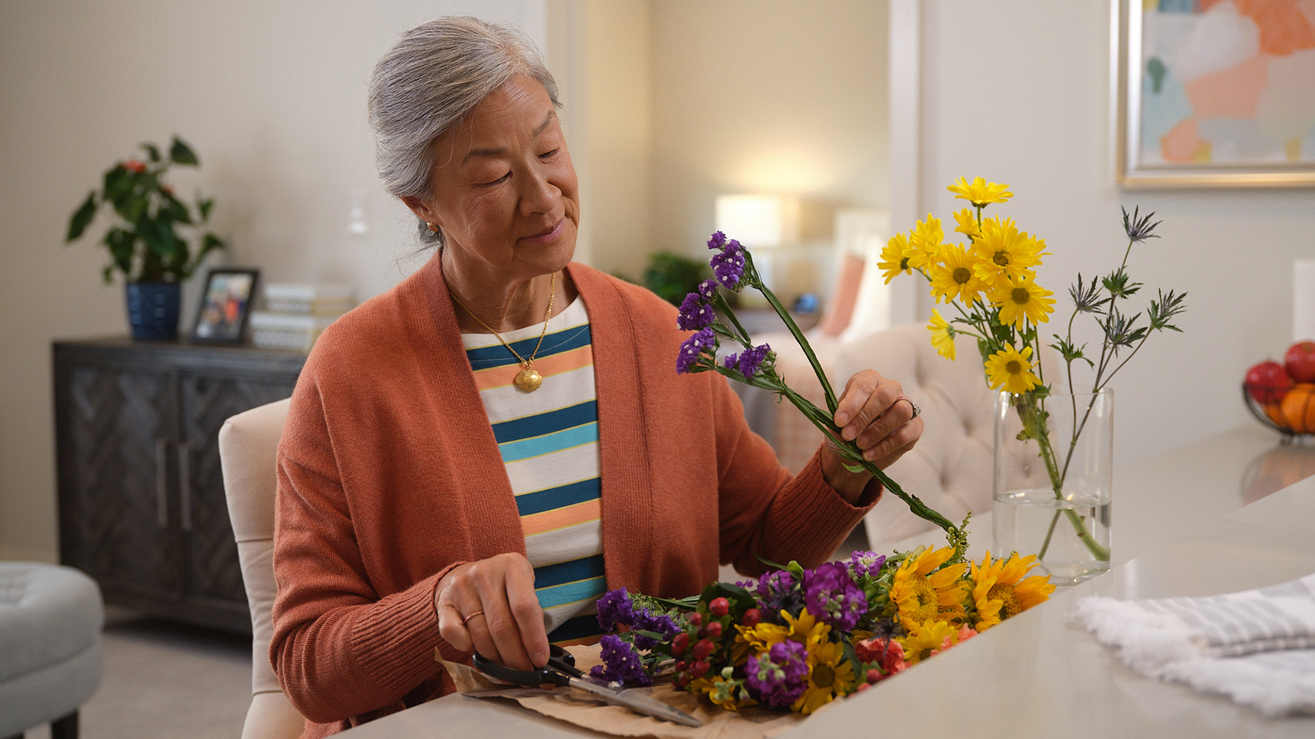 Older female putting together a vase of flowers