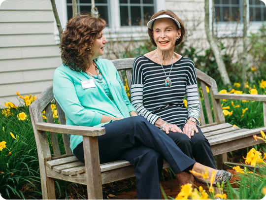Senior woman and Atria employee sitting in the garden on a nice summer day